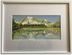 Framed painting of a mountain reflected in a peaceful lake